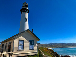 Leuchtturm auf Felsen mit Ozean und Brandung unter blauem Himmel - Lighthouse or light fire on...