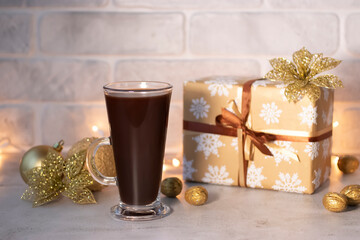 Christmas and New Year concept. A gift in a beautiful package with a ribbon, decorative balls and decorations, and a glass cup with hot chocolate and marshmallows.