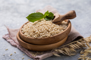  Unpolished brown rice in wooden bowl. Long grain rice background.