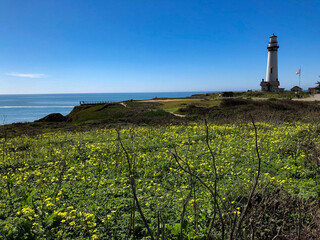 Leuchtturm auf Felsen mit Ozean und Brandung unter blauem Himmel - Lighthouse or light fire on...