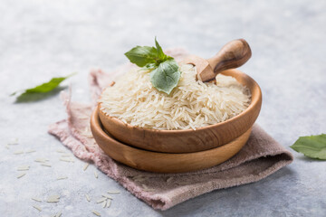 White polished rice in wooden bowl. Long grain rice background.