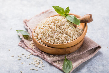  Unpolished brown rice in wooden bowl. Long grain rice background.