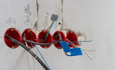 Installation of electrical wiring, red plastic boxes and electrical cables on the wall, repair concept
