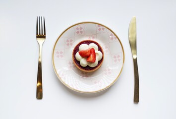 Tart with meringue, raspberry filling and strawberries on a white plate