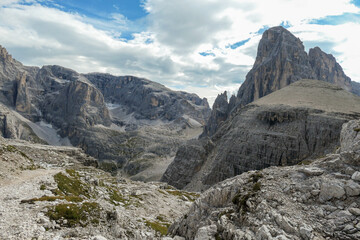 A panoramic view on Italian Dolomites. There are many high and sharp peaks in front, with many landslides. Dangerous climbing. Barely any plants growing in the  area. Raw and unspoiled landscape.