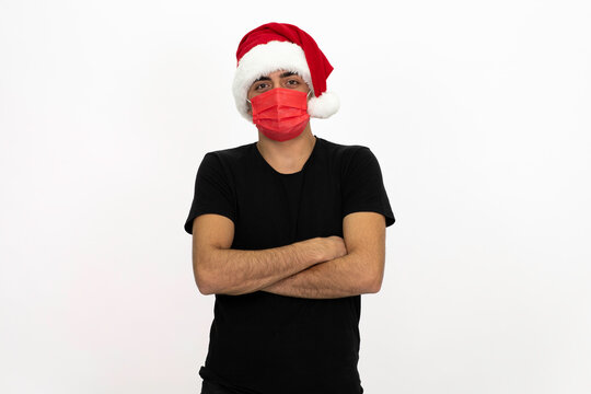 Young man wearing a Santa hat. There is a red medical mask. He is wearing a black shirt. Isolated image white background.