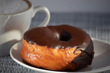 Donut with chocolate on a platter with a cup of coffee