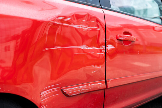 Coche rojo con golpe en la puerta