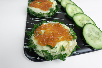 Kanapes with butter and red caviar, and sliced cucumber.