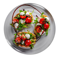 Italian bruschetta with roasted tomatoes, mozzarella cheese, balsamic vinegar and herbs on plate isolated on white background