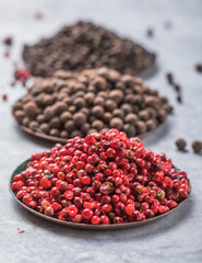 Various kinds of peppercorns in bowls on  stone background. Black pepper. Heap mix of peppercorns