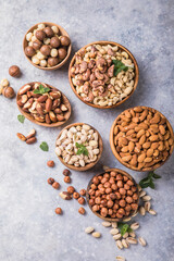 Assortment of nuts in a wooden bowls, on a gray background. Hazelnuts, pistachios, almonds, brazil nut, cashews. Top view
