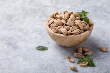 Pistachio nuts in a brown bowl on a concrete background. Healthy eating concept