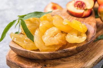 Dried fruits or candied and Fresh peaches with leaves on stone background