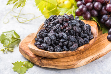 Black raisins  in bowl on stone  background, table top view. Dried fruit, healthy snack food