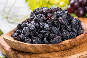 Black raisins  in bowl on stone  background, table top view. Dried fruit, healthy snack food
