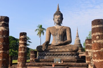 Obraz premium Ancient ruins and Buddha statue in the famous Sukhothai Historical Park. One of Thailand's most impressive World Heritage sites.