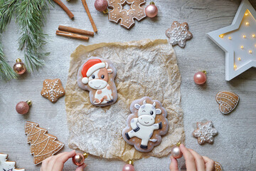 two Christmas gingerbread in glaze in the form of bulls, Christmas symbols 2021, on a white table with New Year's decor, horizontal