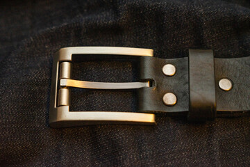 Leather belt with simple rectangular iron buckle on dark blue denim jeans