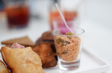 White plate with small portion of couscous and other fingerfood, selective focus