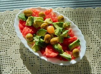 Tomato and avocado salad with olives and a small pickled onion