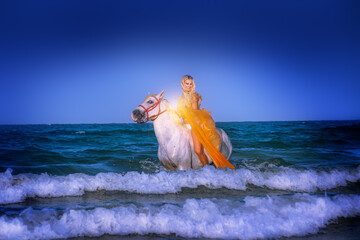 Pretty blond female model horse riding on beach and in the ocean. Horse back riding.