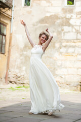 Fototapeta na wymiar Beautiful smiling woman in light white long dress in the city