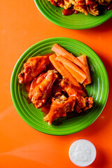 Chicken wings. Chicken wings served spicy buffalo wing sauce and honey barbecue sauce. Served with ranch dressing, blue cheese, celery and carrots. Classic American style bar or pub favorite fare.