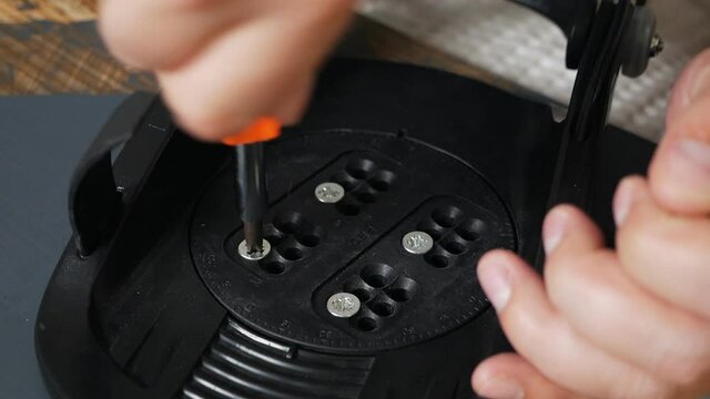 The man's hand attaches the bindings to the snowboard. Prepares the snowboard for winter