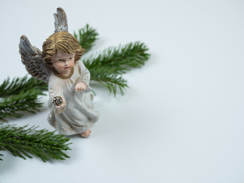 Christmas composition. Angel and fir tree branches on white background. Perspective view.