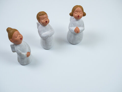Christmas composition. Three singing angels on white background. Perspective view.