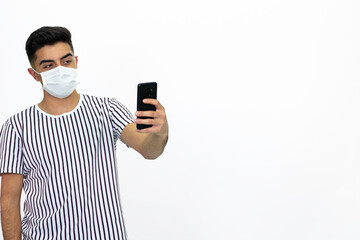Young man wearing a white striped shirt. He's wearing a medical mask. He has a cell phone. White background. Isolated image.