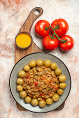 top view roasted eggplant salad on plate on chopping board tomatoes on nude background