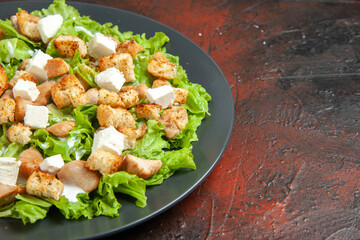 bottom half view caesar salad on oval plate on dark red background
