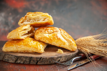 front view penovani khachapuri on wood board knife and fork on dark red background