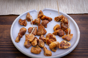 Dried figs in a grey plate on a wooden table. Dried figs are very common in Greece.