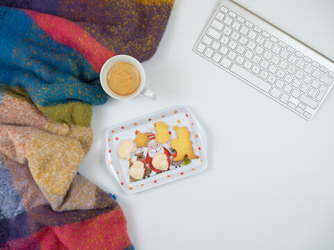 Christmas composition. Scarf with cup of coffee, keyboard and christmas cakes on white background. Flat lay, top view.