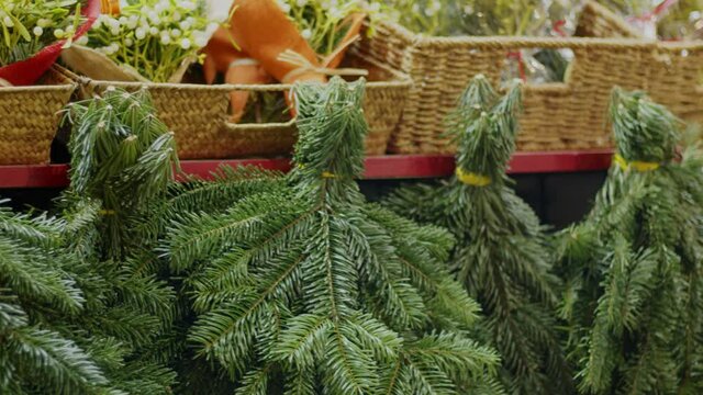 Europe, Spain, Barcelona winter holiday market stall closeup. Christmas tree branches, toys, flowers. Panned video 4k footage.