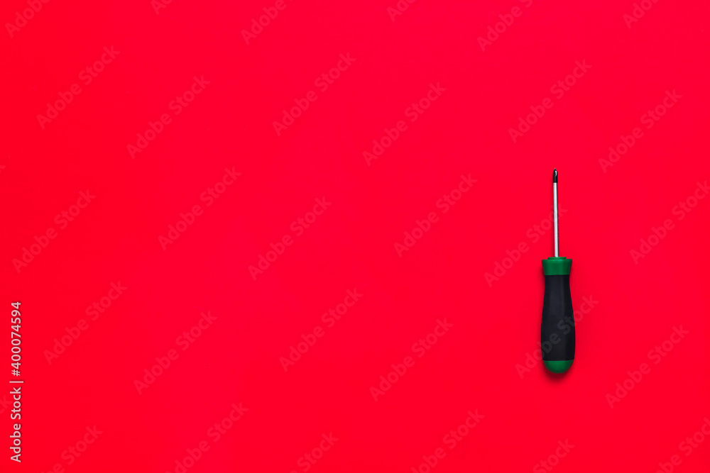 Wall mural quality green building screwdriver tool for repair a car or house on red background. do it yourself 