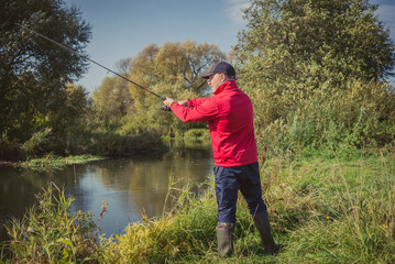 Fishermen fishing with a spinning rod from the shore on a sunny day. Fishing on a sunny day. Man on the river bank throws a spinning rod.