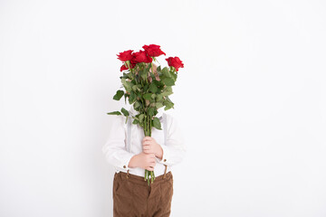 baby toddler boy holding bouquet of red roses in suit on white background. faceless.