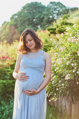 Fototapeta premium Beautiful pregnant woman relaxing in park future mom expecting child.