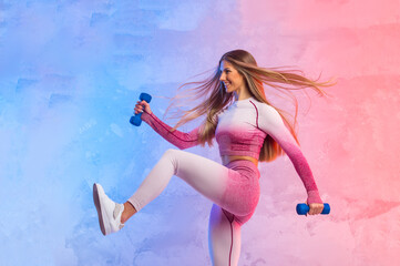 Fitness young woman working out with dumbbells isolated on neon light background. Online workout concept