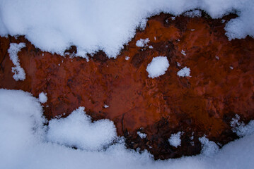 Close up view of red color creek (water full of iron) in winter time 