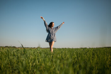 The girl walks in the field in summer.