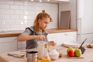Obraz na płótnie Canvas Happy teenager girl is preparing apple cake in the kitchen.