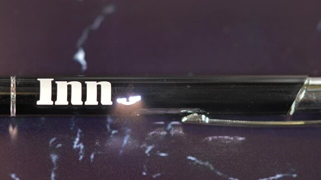Laser engraving on a black metal pen. Modern industrial technologies. Word  Innovation