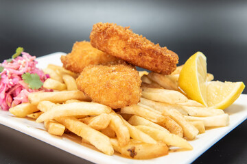 Breaded halibut fish and chips served with french fries and lemon garnishment for a plate of...