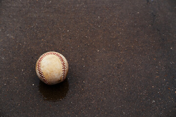 Old used baseball on wet concrete, rain out concept for game.