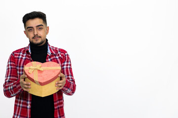 Young male holding a heart-shaped gift box in his hand. Wearing a striped shirt. Isolated image and white background.